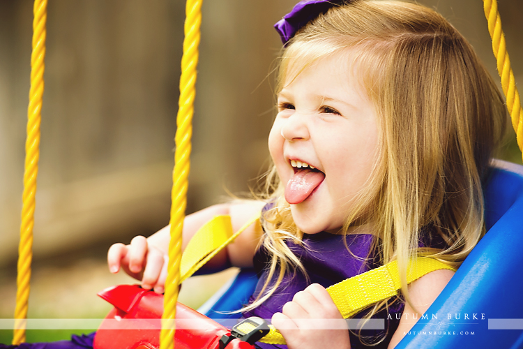 colorado childrens portrait photographer toddler girl in swing laughing lifestyle family portrait